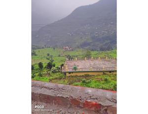 a building in a field with a mountain in the background at Hotel Rudra and Restaurant, Gopeshwar in Gopeshwar