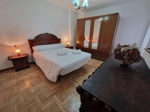 1 dormitorio con 1 cama blanca grande y suelo de madera en 168A Apartamento en el Natahoyo , Gijón en Gijón