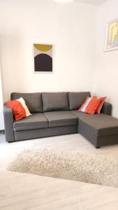 un sofá gris en una sala de estar con almohadas naranjas en Pikkuhuoneisto loistosijainnilla Töölössä en Helsinki
