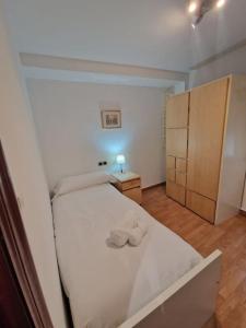 Un pequeño dormitorio con una cama blanca y un armario en 168A Apartamento en el Natahoyo , Gijón en Gijón