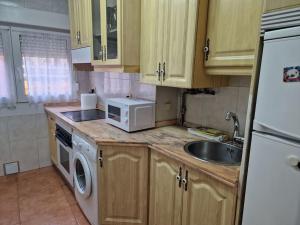 cocina con fregadero y microondas blanco en 168A Apartamento en el Natahoyo , Gijón en Gijón