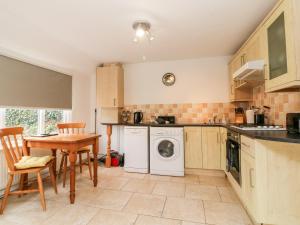 a kitchen with a washing machine and a table and chairs at Priory House Cottage in Barnstaple