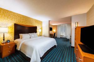 a hotel room with a bed and a flat screen tv at Fairfield Inn Battle Creek in Battle Creek