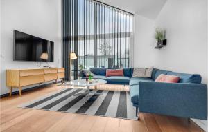 a living room with a blue couch and a tv at Amazing Home In Strby With House Sea View in Strøby