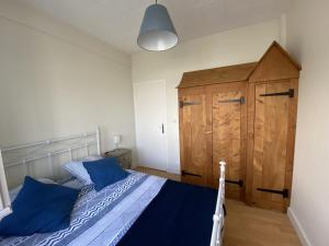 a bedroom with a bed with blue pillows and a wooden cabinet at L améthystes in Crozon