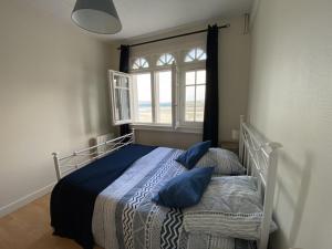 a bedroom with a bed with blue pillows and a window at L améthystes in Crozon
