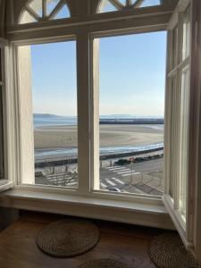 a room with two large windows looking out at the beach at L améthystes in Crozon