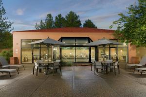 an outdoor patio with tables and chairs and umbrellas at Courtyard by Marriott Albuquerque Airport in Albuquerque