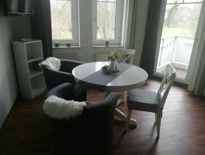 une salle à manger avec une table et des chaises blanches dans l'établissement Ferienwohnung Am Kurpark, à Bad Klosterlausnitz