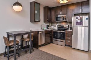 a kitchen with wooden cabinets and a table and a refrigerator at Residence Inn by Marriott Charlotte Northlake in Charlotte