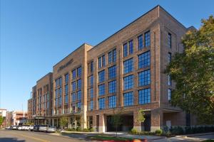 a large brick building with many windows on a street at The Alamite, Tuscaloosa, a Tribute Portfolio Hotel in Tuscaloosa