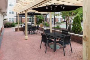 patio ze stołami, krzesłami i parasolem w obiekcie Residence Inn Boston Marlborough w mieście Marlborough