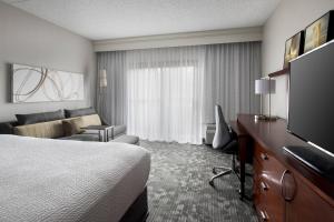 a hotel room with a bed and a couch and a television at Courtyard by Marriott Lincroft Red Bank in Red Bank