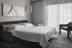 a bedroom with a bed and a chair and a window at Courtyard by Marriott Lincroft Red Bank in Red Bank
