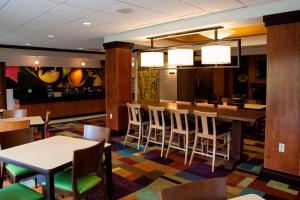 a restaurant with tables and chairs and a bar at Fairfield Inn & Suites Bedford in Bedford