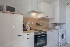 a kitchen with white cabinets and a stove top oven at Appartement tout confort in Fay-aux-Loges