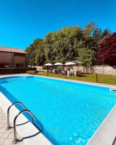 ein blauer Pool mit Tischen und Sonnenschirmen in der Unterkunft Hotel Isola Di Caprera in Mira