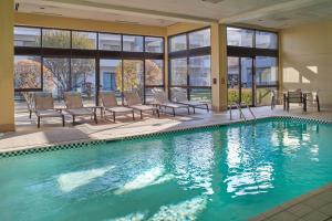 una piscina con sillas, una mesa y ventanas en Courtyard Chicago Oakbrook Terrace, en Oakbrook Terrace