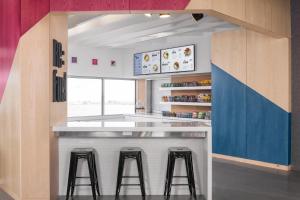 a kitchen with a counter with stools in it at Aloft Oklahoma City Quail Springs in Oklahoma City