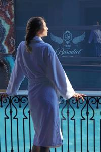 Una mujer con un vestido azul parada junto a una valla en CUNDA BARADİEL Hotel en Ayvalık