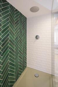 uma casa de banho com uma parede em azulejo verde e branco em Stadtmauer-Apartments - Neue helle Studio Wohnung direkt an der historischen Stadtmauer em Nördlingen