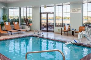 una piscina en una habitación de hotel con sillas y mesas en Courtyard Richland Columbia Point, en Richland