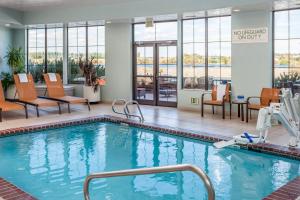 uma piscina num quarto de hotel com cadeiras e mesas em Courtyard Richland Columbia Point em Richland