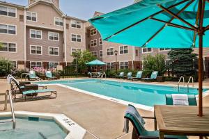 a pool with tables and chairs and a blue umbrella at Residence Inn Fairfax Merrifield in Merrifield