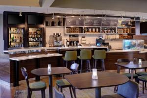 Un restaurante con mesas y sillas y un bar. en Courtyard Detroit Dearborn, en Dearborn