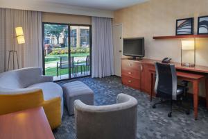 a hotel room with a desk and a television at Courtyard Detroit Dearborn in Dearborn