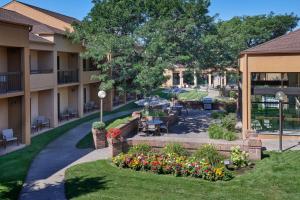 un complejo de apartamentos con un patio con mesas y flores en Courtyard Detroit Dearborn en Dearborn