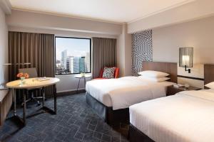 大阪的住宿－新大阪車站萬怡酒店，酒店客房设有两张床、一张桌子和一个窗户。