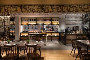 a restaurant with tables and chairs and a kitchen at Courtyard by Marriott Shin-Osaka Station in Osaka