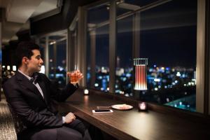 a man in a suit sitting at a table with a drink at Courtyard by Marriott Shin-Osaka Station in Osaka