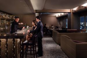 a man and woman sitting at a bar in a restaurant at Courtyard by Marriott Shin-Osaka Station in Osaka