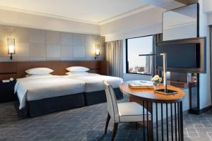 a hotel room with a bed and a table and a tv at Courtyard by Marriott Shin-Osaka Station in Osaka
