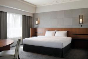 a hotel room with a large bed and a table at Courtyard by Marriott Shin-Osaka Station in Osaka