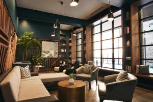 a living room with couches and chairs and windows at Kinley Chattanooga Southside, a Tribute Portfolio Hotel in Chattanooga