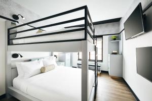 a bedroom with a loft bed with a white bed at Kinley Chattanooga Southside, a Tribute Portfolio Hotel in Chattanooga