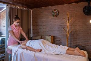 a woman in a mask treating a woman on a bed at Hotel Pousada Natural in Brotas