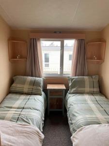 two beds in a small room with a window at Chalet 40, Cleethorpes in Humberston