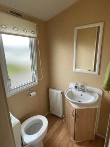 a bathroom with a sink and a toilet and a window at Chalet 40, Cleethorpes in Humberston