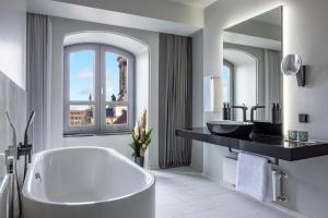 La salle de bains est pourvue d'une baignoire, d'un lavabo et d'un miroir. dans l'établissement Hotel Luc, Autograph Collection, à Berlin