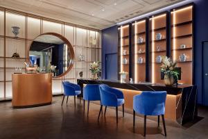 a dining room with blue chairs and a table and a mirror at Hotel Luc, Autograph Collection in Berlin