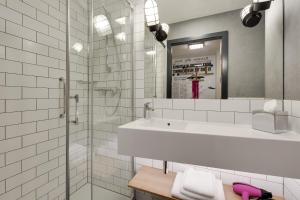 a white bathroom with a sink and a shower at Moxy Katowice Airport in Pyrzowice