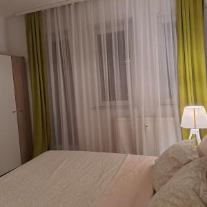 een slaapkamer met een bed en een raam met een lamp bij Prishtina Center Apartment in Pristina