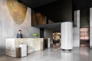 a man standing behind a counter in a lobby at Melbourne Marriott Hotel Docklands in Melbourne