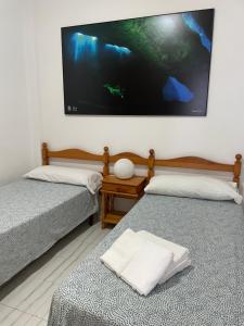 Habitación con 2 camas y TV grande en la pared. en ROCAMAR en La Restinga