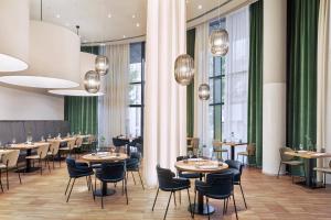 ein Restaurant mit Tischen und Stühlen und großen Fenstern in der Unterkunft Courtyard by Marriott Vienna Prater/Messe in Wien