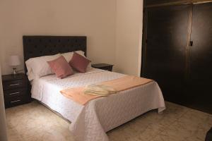 een slaapkamer met een bed met witte lakens en roze kussens bij ALOJAMIENTO CON PARQUEO CERCA A LA BASÍLICA in Buga